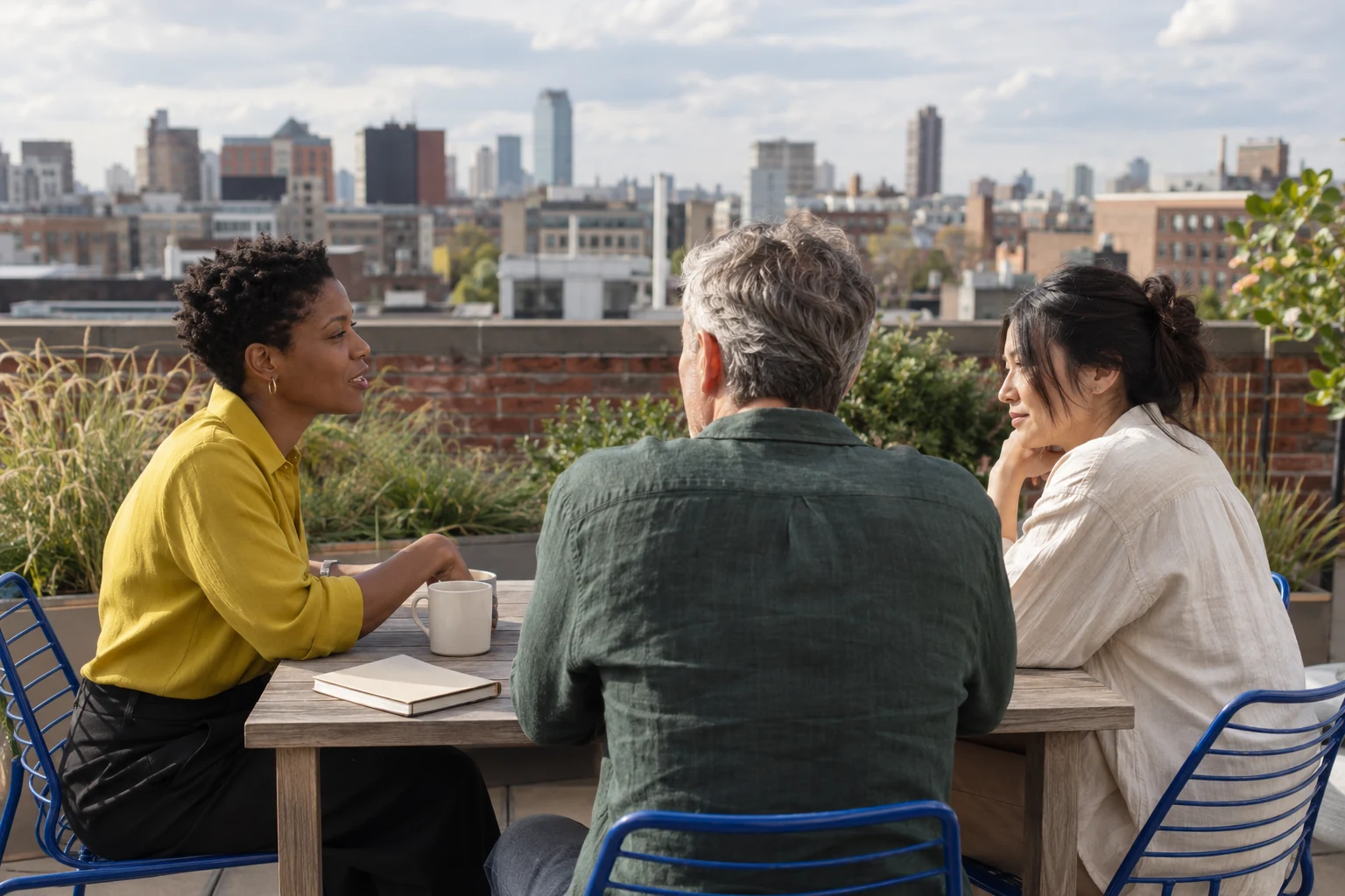Three colleagues talking around a table on a city rooftop terrace