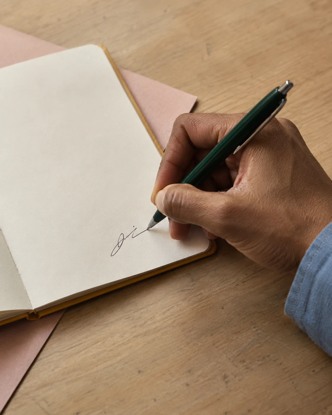 A hand signing a note with a fountain pen